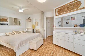A bedroom with a bed, a bench, a wardrobe, and a mirror.