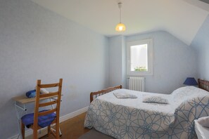 Ein Schlafzimmer mit Bett, Stuhl, Schreibtisch und Fenster.