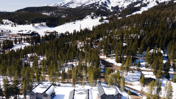 A lodge with multiple buildings surrounded by snow-covered mountains and dense forests. - Alpine Nest Bridger Bowl A (Bozeman)