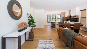A modern living room with a sofa, a coffee table, and a dining area with a table and chairs. - Alpine Nest Bridger Bowl A (Bozeman)