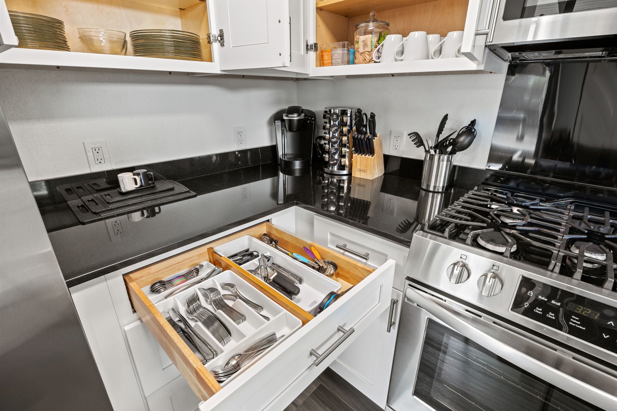 A modern kitchen with a built-in dishwasher, a stainless steel stove, and a drawer organizer with utensils.