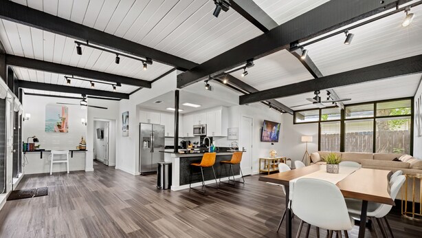 A spacious open-plan living area with a kitchen, dining table, and seating. - Stylish Home near Love-Field Airport, King & Queen Beds with a Large Yard (Dallas)