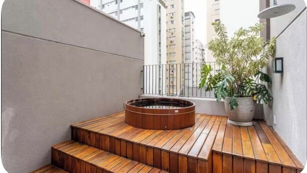 A rooftop terrace with a circular hot tub, wooden steps, and a potted plant. - Jardim Paulista Studio Completo (Jardim Paulista São Paulo)