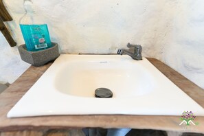 A white bathroom sink with a single faucet, a soap dispenser, and a stone basin. - ARIANTIY HOSTAL (Mocoa)