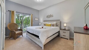 Un dormitorio con una cama grande, una mesita de noche, una silla y una ventana con cortinas.