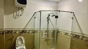 Un espace douche d’angle avec une porte en verre, des toilettes équipées d’un bidet et un porte-serviettes.
