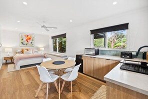 A modern kitchen with a dining area, a bed with a view, and a ceiling fan. - Bella Vita (Lorne)