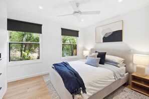 A bedroom with a bed, two bedside lamps, a ceiling fan, and two windows with blinds. - Bella Vita (Lorne)
