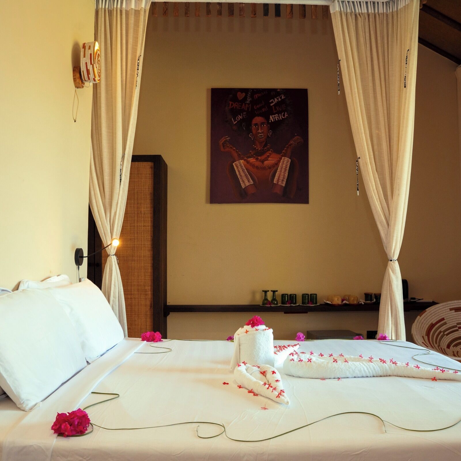 A hotel room with a bed, white linens, a poster on the wall, and a curtain.