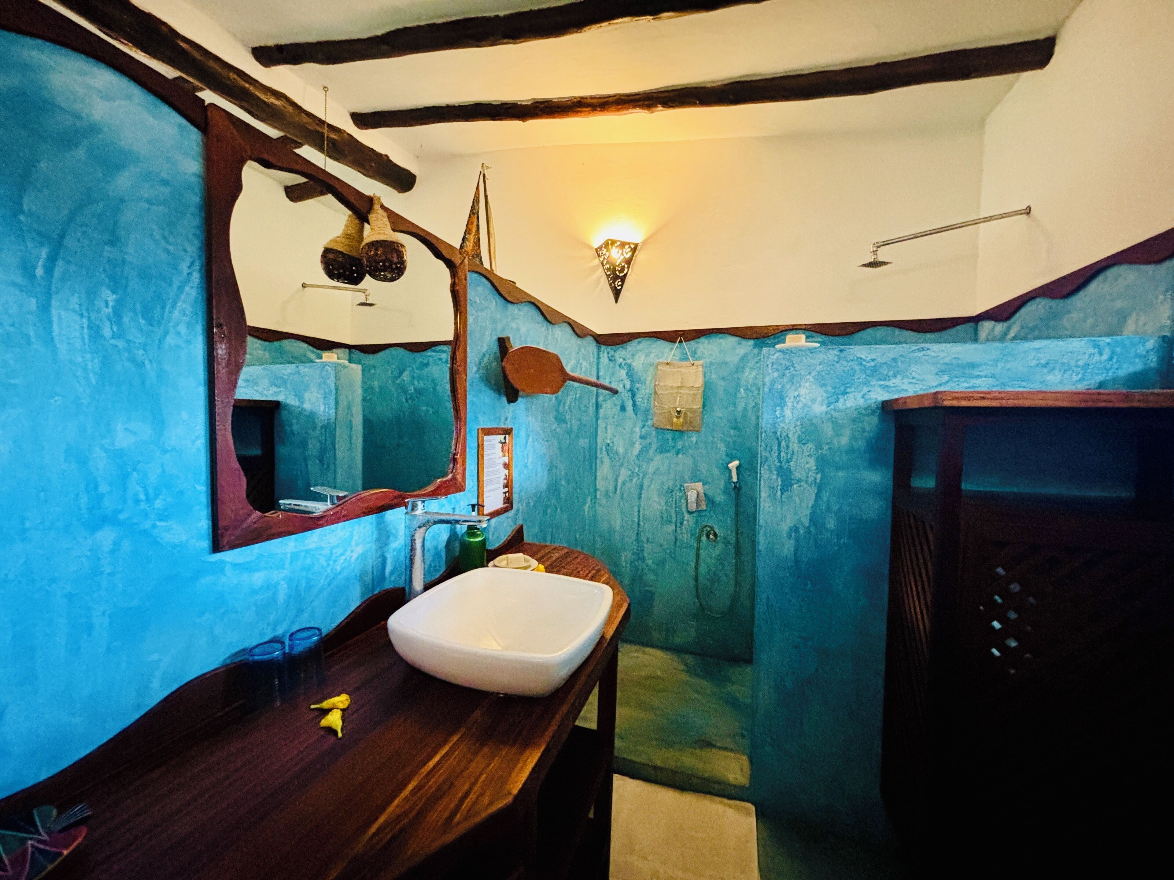 Une salle de bain avec un meuble-lavabo en bois, un lavabo blanc, un miroir et un espace douche.