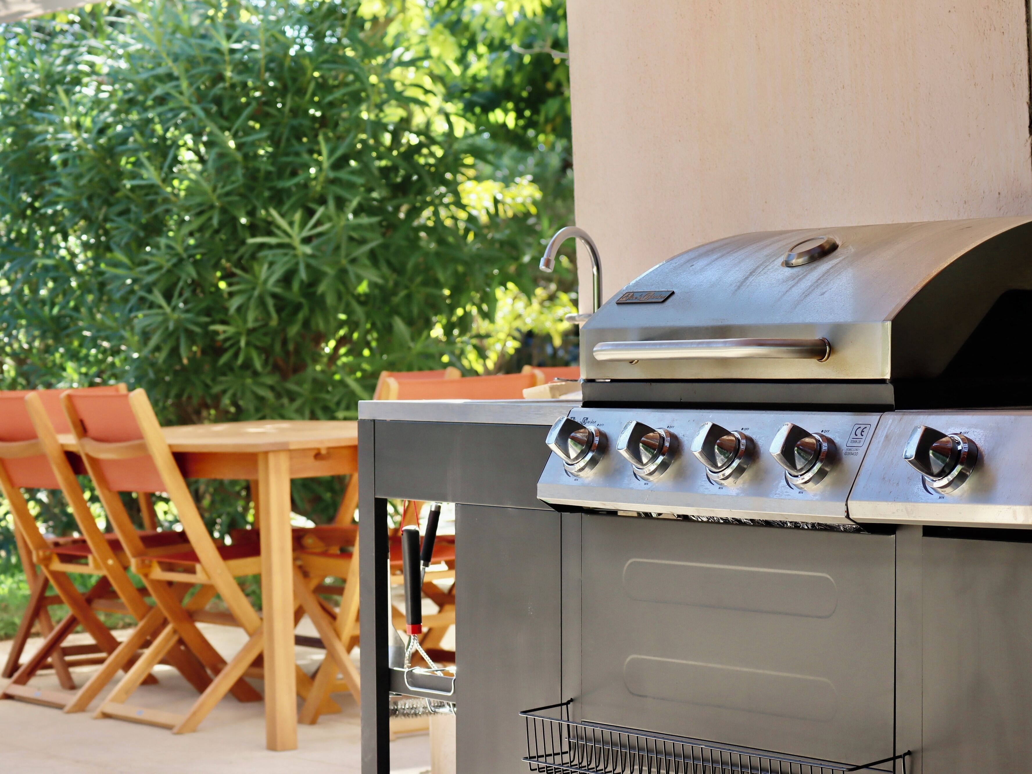 An outdoor grill with four burners, a stainless steel finish, and a side shelf.