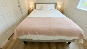 A neatly made bed with a patterned bedspread, two bedside lamps, and a window with a view of greenery. - Family-Friendly Retreat in Marysville (Marysville)