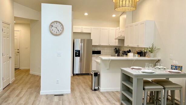 A modern kitchen with white cabinets, stainless steel appliances, and a dining area with a table and stools. - Family-Friendly Retreat in Marysville (Marysville)
