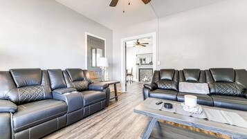 Un salon moderne avec deux canapés en cuir noir, une table basse en bois et un ventilateur de plafond.