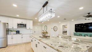 A modern kitchen with white cabinets, a granite countertop, a chandelier, and a built-in microwave. - Furnished Outdoor Area! Family Home in Spring Hill (Spring Hill)
