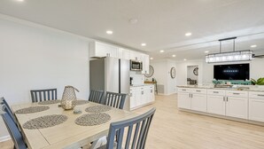 A modern kitchen with white cabinets, a built-in microwave, and a large island with a sink. - Furnished Outdoor Area! Family Home in Spring Hill (Spring Hill)