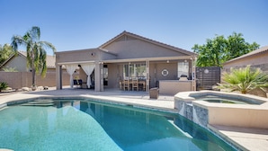 Ein Wohnhaus mit Pool, Terrasse und überdachter Außenbereich mit Sitzgelegenheiten.