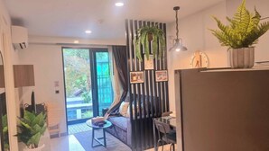 A modern living room with a sofa, a dining table, and a kitchen area.