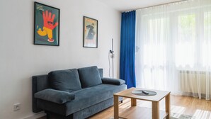Un salon moderne avec un canapé gris foncé, une table basse en bois et deux œuvres d’art encadrées accrochées au mur.