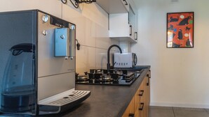 Une cuisine moderne équipée d’une machine à expresso intégrée, d’un four à micro-ondes et d’une cuisinière à gaz.