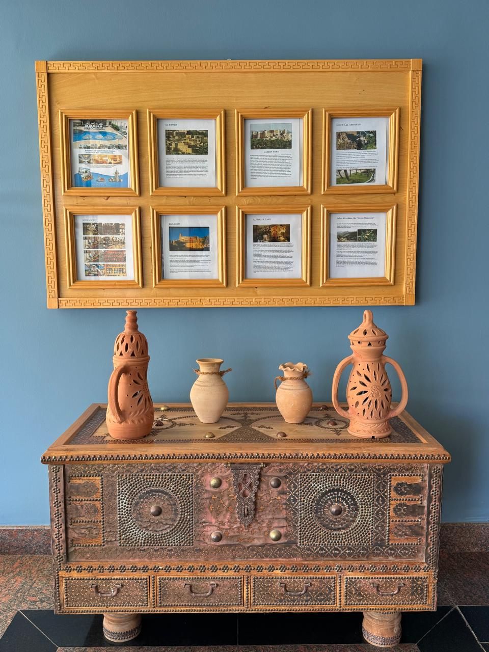 A display of framed documents and traditional pottery on a decorated cabinet.