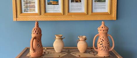 A display of framed documents and traditional pottery on a decorated cabinet.