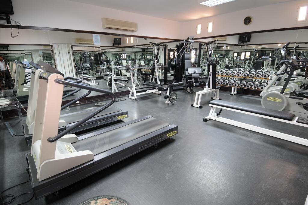 A gym with treadmills, weight machines, and dumbbells.