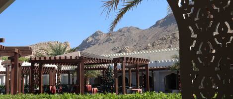 An outdoor seating area with wooden pergolas and tables, a Christmas tree, and a mountain backdrop.
