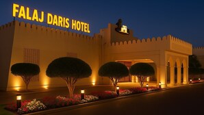 The Falaj Daris Hotel facade at dusk with illuminated signage, a lion statue, and traditional architecture. - FALAJ DARIS HOTEL (Nizwa)