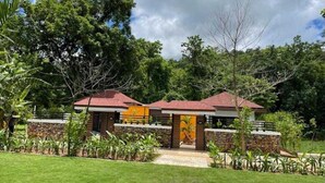 A two-story building with a red roof, surrounded by lush greenery and trees. - Aranya Nivas Resort (Samakhunta)