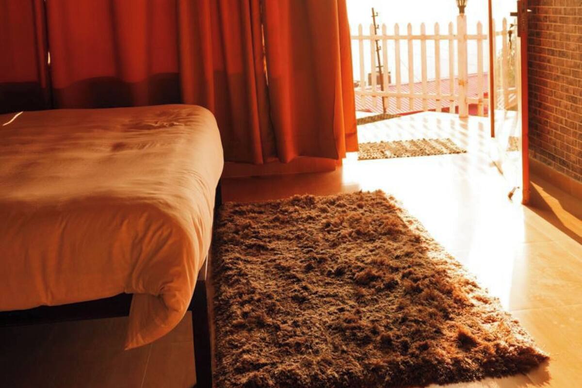 Une chambre à coucher avec un lit, un tapis et une vue sur une clôture blanche et un lampadaire situés à l’extérieur.