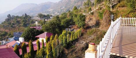 A hillside village with terraced houses, a white fence, and a paved path.