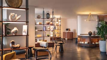 Relax in a cozy seating area with a sofa, armchairs, and a coffee table, surrounded by books and decorative items.