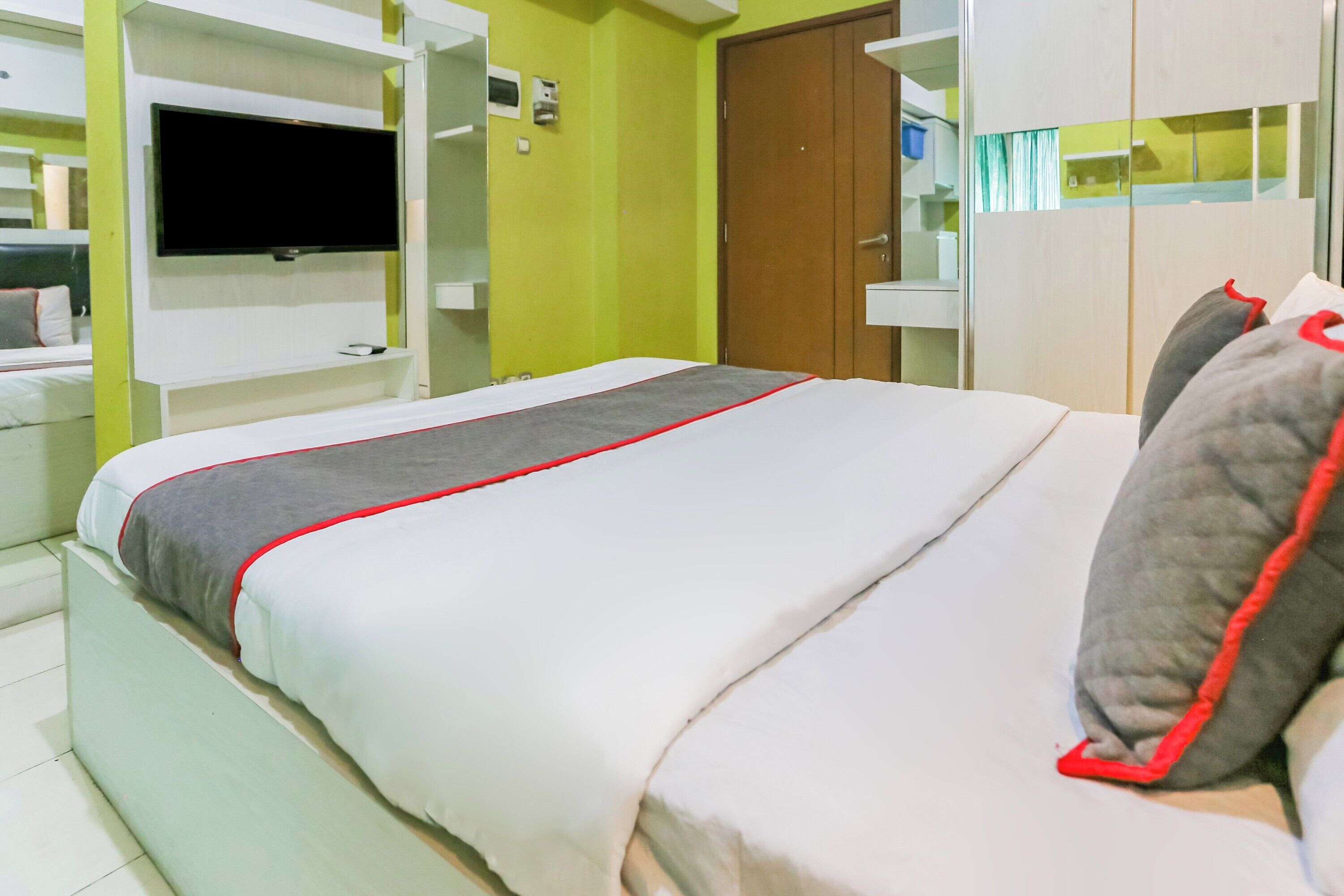 A hotel room with a bed, a television mounted on the wall, and a wardrobe.