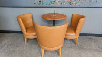Two brown leather chairs and a small wooden table in a room with a tiled floor and a colorful mural on the wall.