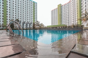 Ein Swimmingpool mit glatter, blauer Wasseroberfläche, umgeben von einer gefliesten Liegefläche.