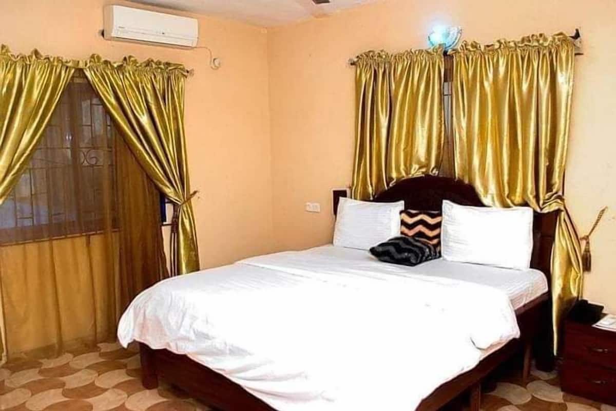 A hotel room with a bed, curtains, and a nightstand.