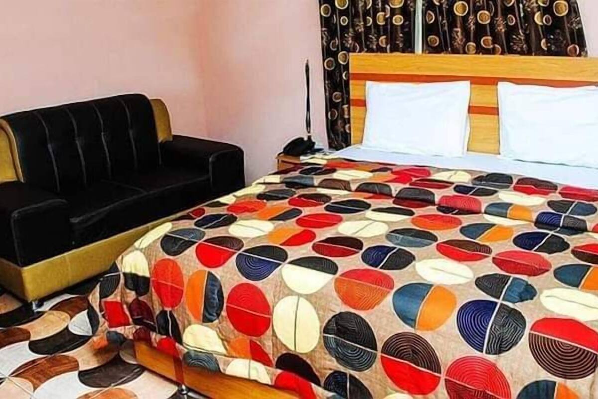 A room with a bed, a black sofa, and a patterned bedspread.