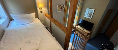 A bedroom with a bed, a desk with a computer, and a staircase.