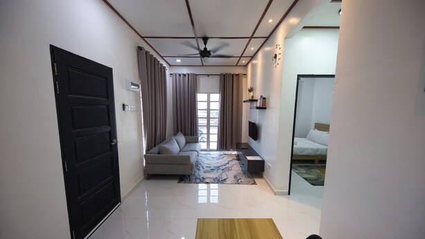 A modern hotel room with a sofa, a TV, a bed, and a dining area with a table and chairs.