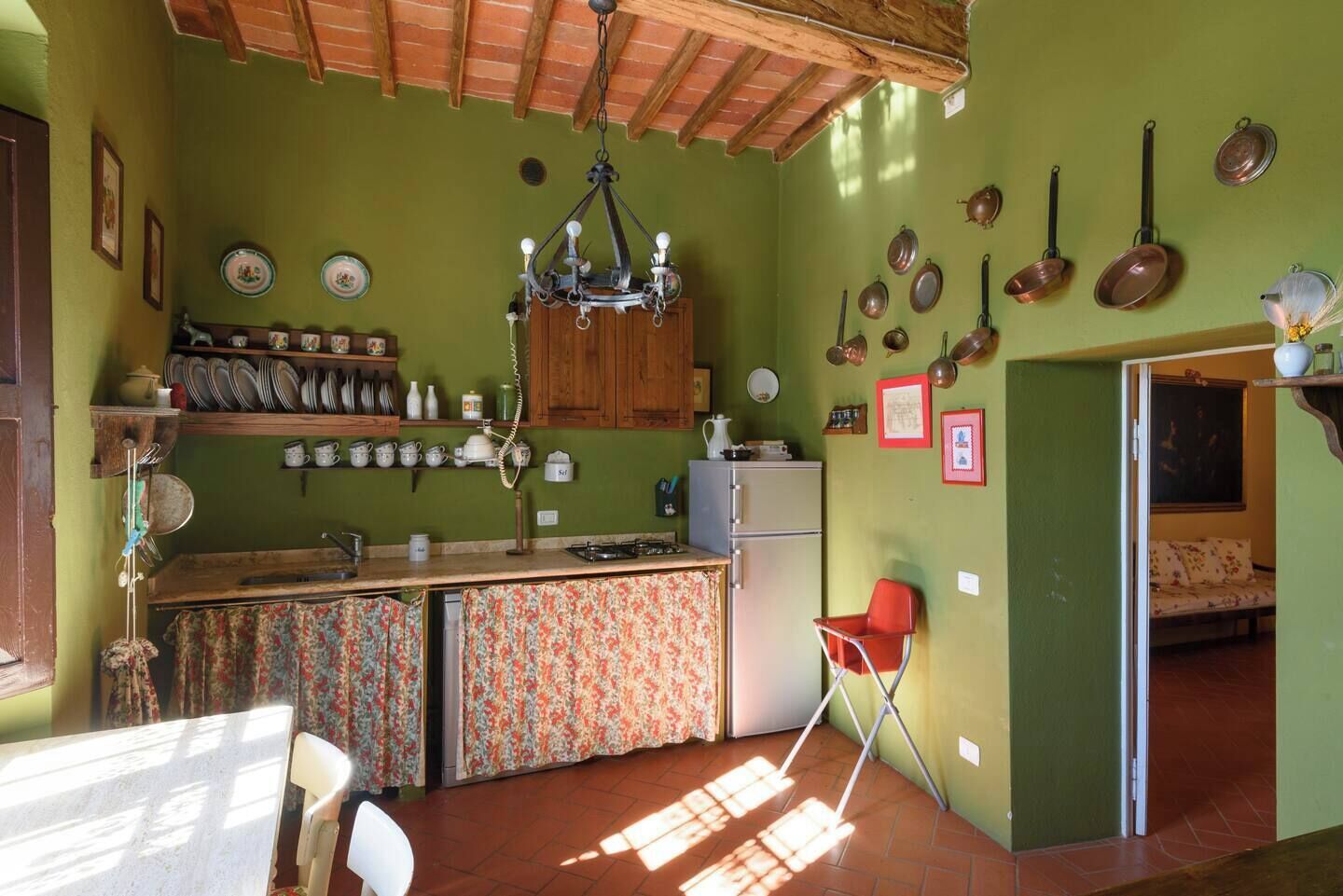 Una cocina con techo de madera, un refrigerador, un lavamanos y una silla.