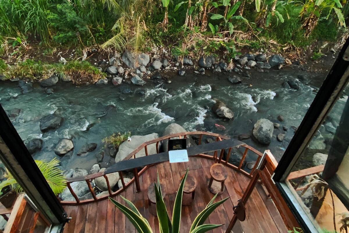 A wooden deck with a view of a river and surrounding vegetation.