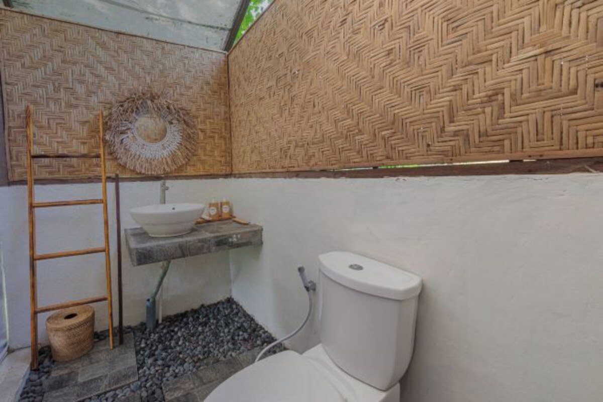 Un baño pequeño con inodoro, lavamanos y un muro tejido.