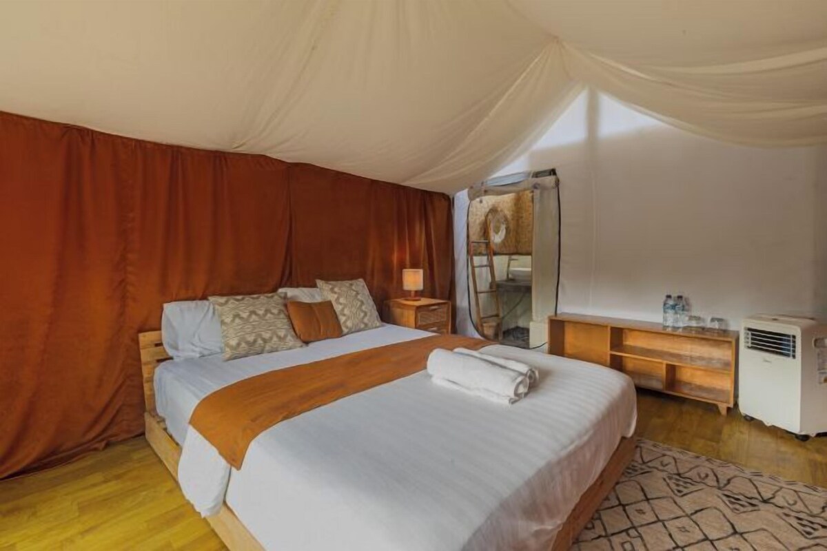 Un dormitorio con una cama grande, cabecera de madera, mesitas de noche, un espejo y un calentador pequeño.