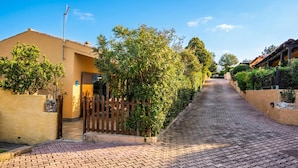 A paved pathway leading to a building with a wooden gate and a satellite dish.