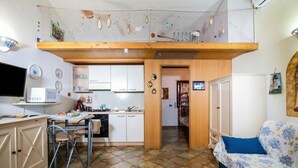 A compact kitchen with a dining area, a sofa, and a TV.