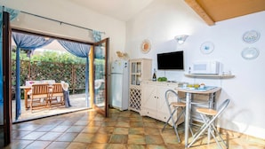 A kitchen with a dining area, a TV, and a refrigerator.
