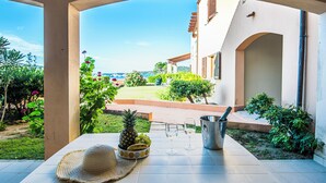 Un patio con una mesa dispuesta para dos, que incluye una piña, uvas, un sombrero y una copa de vino.