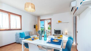 Una sala de estar moderna con comedor, un sofá, televisor y zona de cocina.