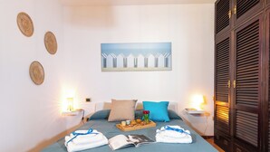 Una cama bien hecha con toallas, una bandeja con artículos para el desayuno y un cuadro en la pared.